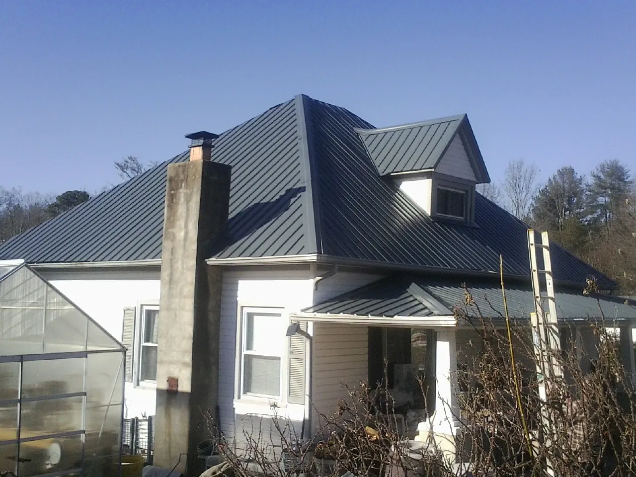 Dark blue standing seam metal roof on a white farmhouse with dormer — Slate & Tile Roof Repair by Roofing Brothers in Linkwood