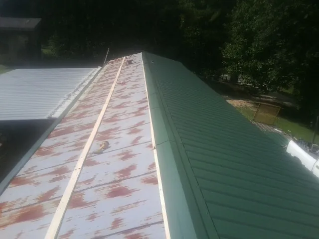 Old rusted panels beside newly installed green metal roofing — Wind Damage Roof Repair by Roofing Brothers in Linkwood