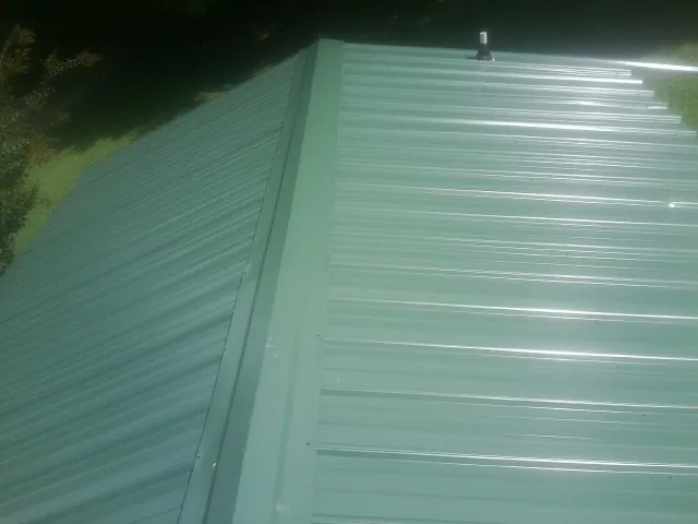 New green metal panels meeting at the ridge of a roof — Flat Roof Repair work by our crew in Linkwood