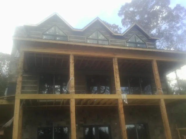 Dormers and porch framing on a large log home under construction — Roof Coating work by our crew in Linkwood