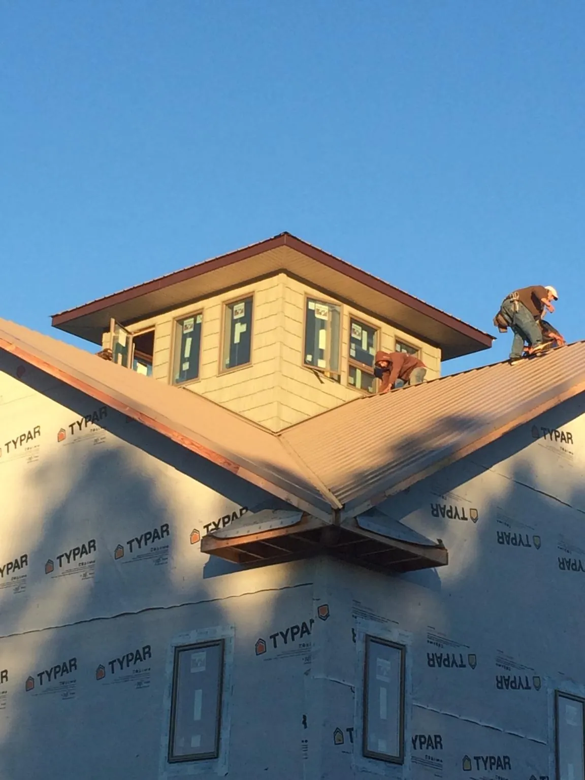 Roofers working around a rooftop cupola on a new metal roof at sunset — Roof Waterproofing in Linkwood by Roofing Brothers